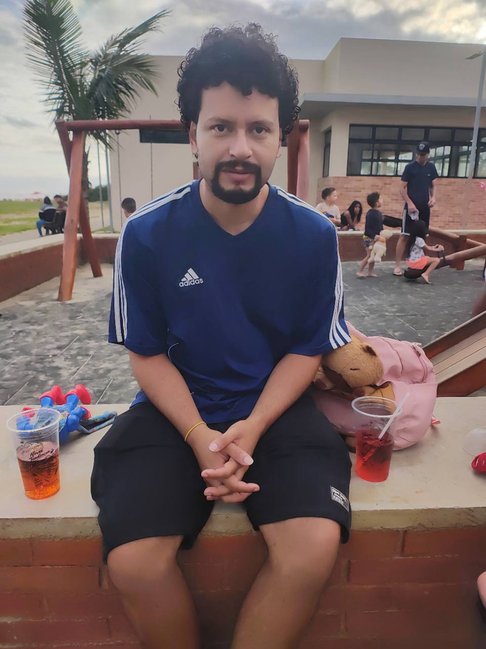 Foto de referência: camisa esportiva azul com gola V, mangas curtas e listras claras, vestida por uma pessoa.